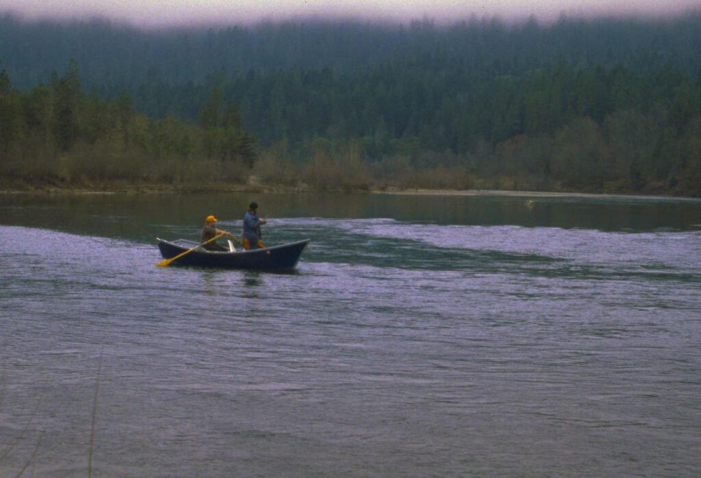 Two men fishing on a drift boat on a river